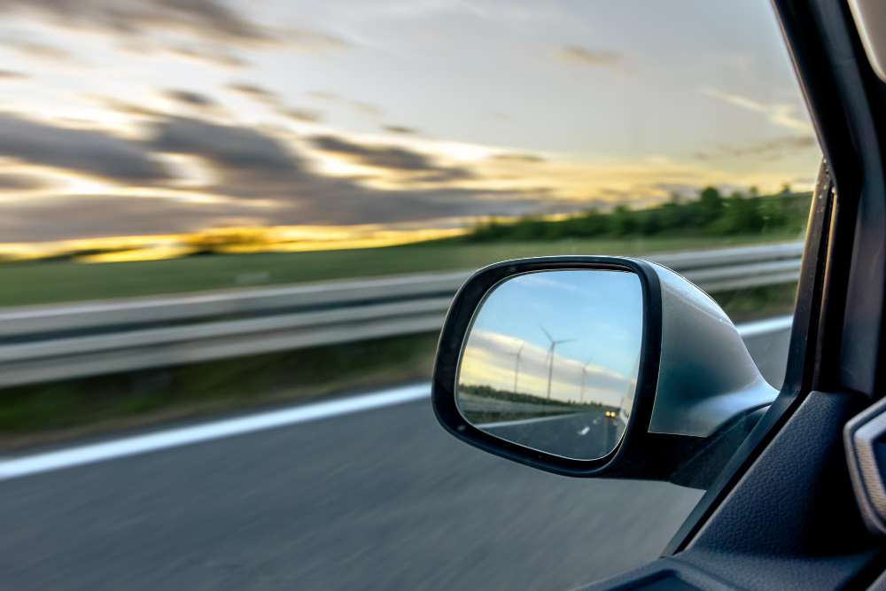 Side view mirror view from a passenger in a moving car, representing Comparison of Wild Coast and Garden Route coastlines in South Africa